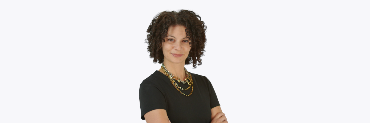 woman with black shirt and black curly hair smiling with arms folded